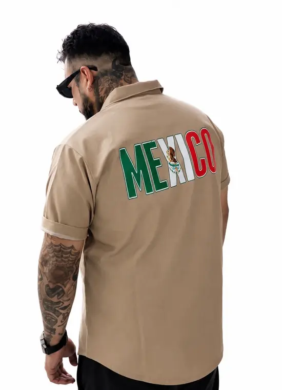 Man wearing a tan Mexico button-up shirt with flag-colored lettering on the back