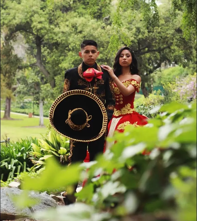Charro couple portrait in a garden with a mariachi sombrero