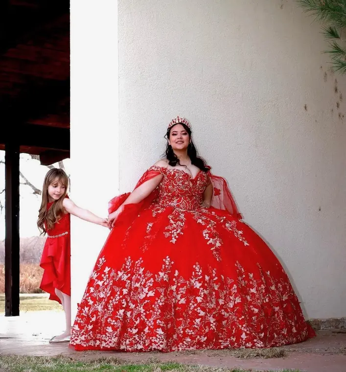 Quinceañera in a red gown holding her little sister's hand